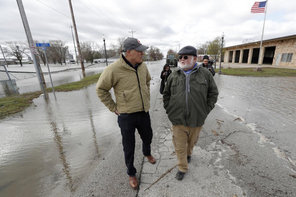 Inslee, left, talks with climate analyst John Davis, of Hamburg, Iowa, while touring flood damage.