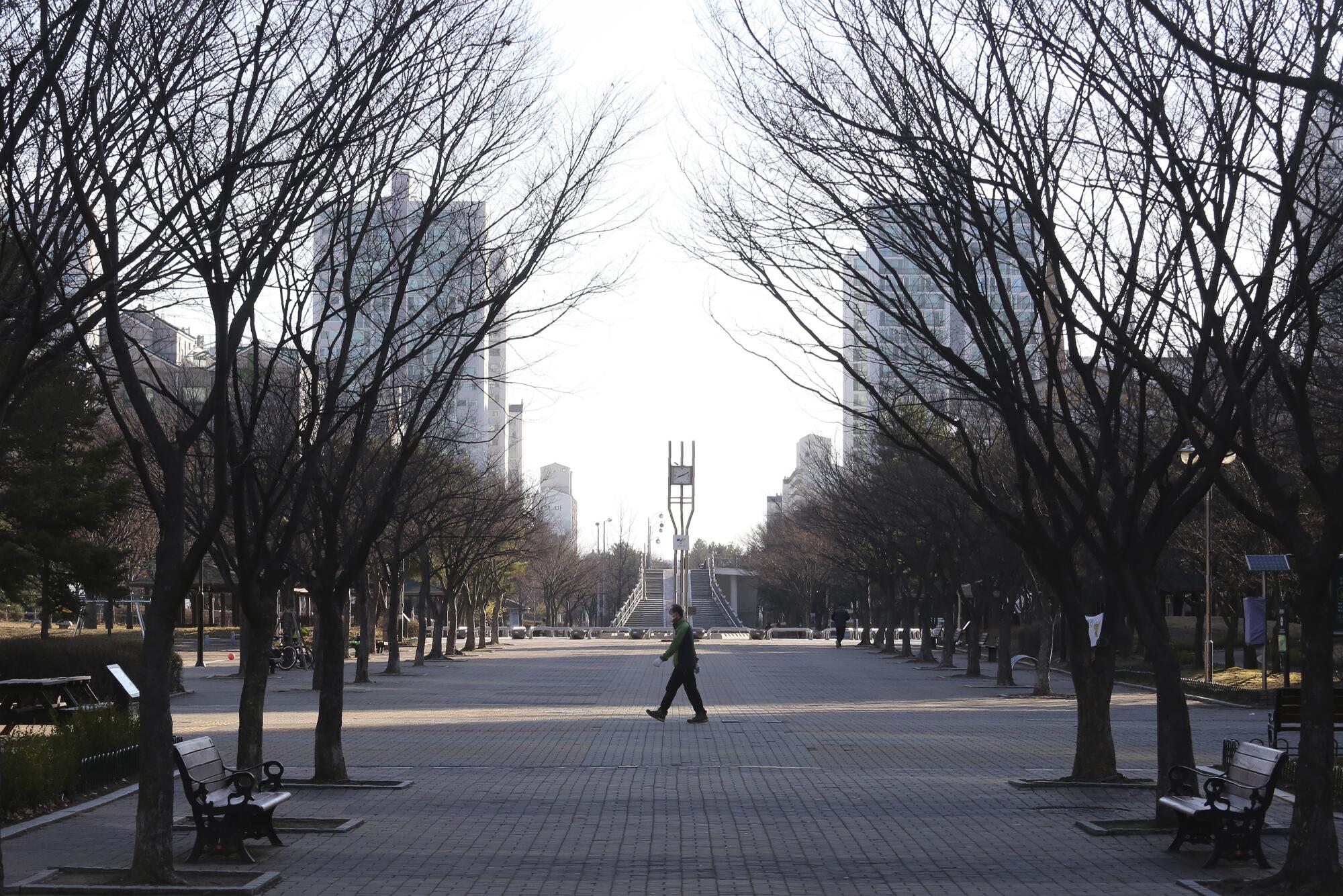 A man wearing a mask walks in a nearly empty park March 22 in Goyang, South Korea.