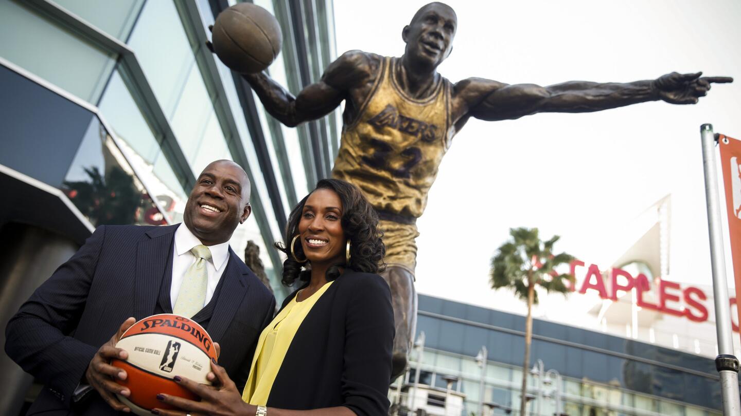 Lakers great Magic Johnson, left, and Sparks legend Lisa Leslie pose beneath a statue of Johnson outside Staples Center while announcing the sale of the Sparks to an investment group led by Johnson and Dodgers owner Mark Walter in February 2014.