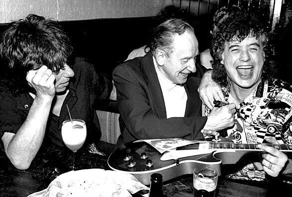 Guitar designer Les Paul, center, who pioneered multi-track rock music recording, signs former Led Zepplin guitarist Jimmy Page's chest after signing his guitar at a 72nd birthday party thrown for Les Paul by the Gibson Guitar Company at New York's Hard Rock Cafe, Monday, June 11, 1987. Guitarist Jeff Beck is at left. (AP Photo/John Bellissimo)