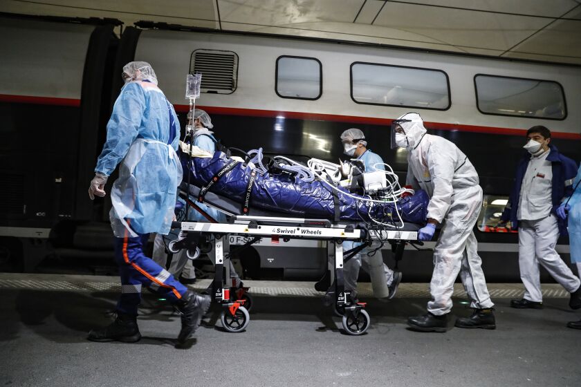 Medical staff embark a patient infected with the COVID-19 virus in a train at the Gare d'Austerlitz train station Wednesday April 1, 2020 in Paris. France is evacuating 36 patients infected with the coronavirus from the Paris region onboard two medicalized high-speed TGV trains. The patients, all treated in intensive care units (ICU), are being transferred to several hospitals in Britany, as western France is less impacted by the epidemic. The new coronavirus causes mild or moderate symptoms for most people, but for some, especially older adults and people with existing health problems, it can cause more severe illness or death. (Thomas Samson, Pool via AP)