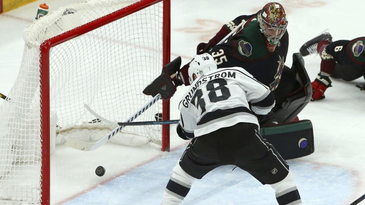 Kings right wing Carl Grundstrom (38) scores a goal against Arizona Coyotes goaltender Darcy Kuemper, top right, during the third period.