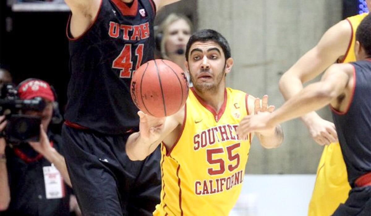 USC's Omar Oraby passes the ball away between Utah defenders during the Trojans' loss Thursday to the Utes, 84-66.