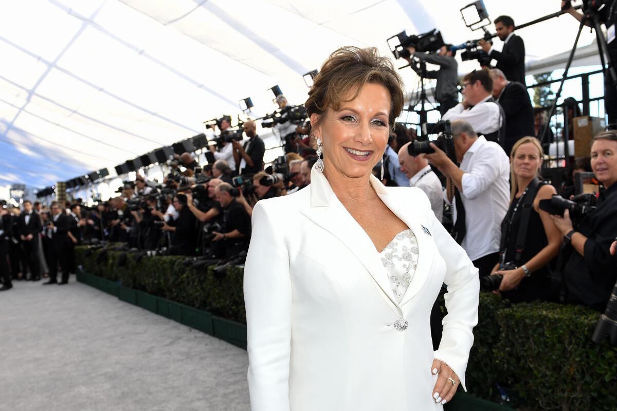 Gabrielle Carteris in a white suit in front of photographers.