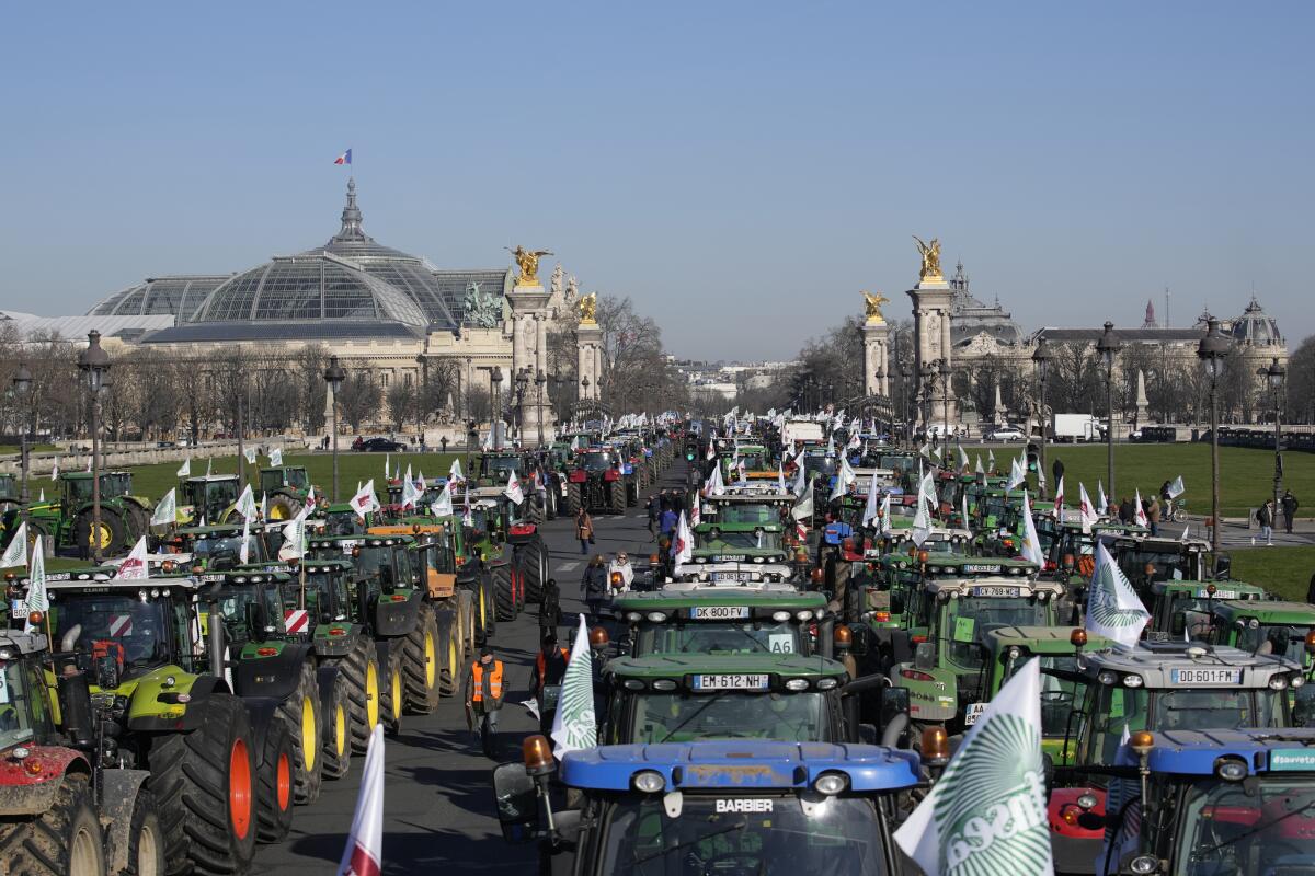 Tractors park in front of the Grand Palais museum, left, Wednesday, Feb. 8, 2023 in Paris. French sugarbeet and other farmers disrupt Paris traffic with hundreds of tractors to protest an EU pesticide ban they say will devastate their livelihoods and industry. (AP Photo/Christophe Ena)