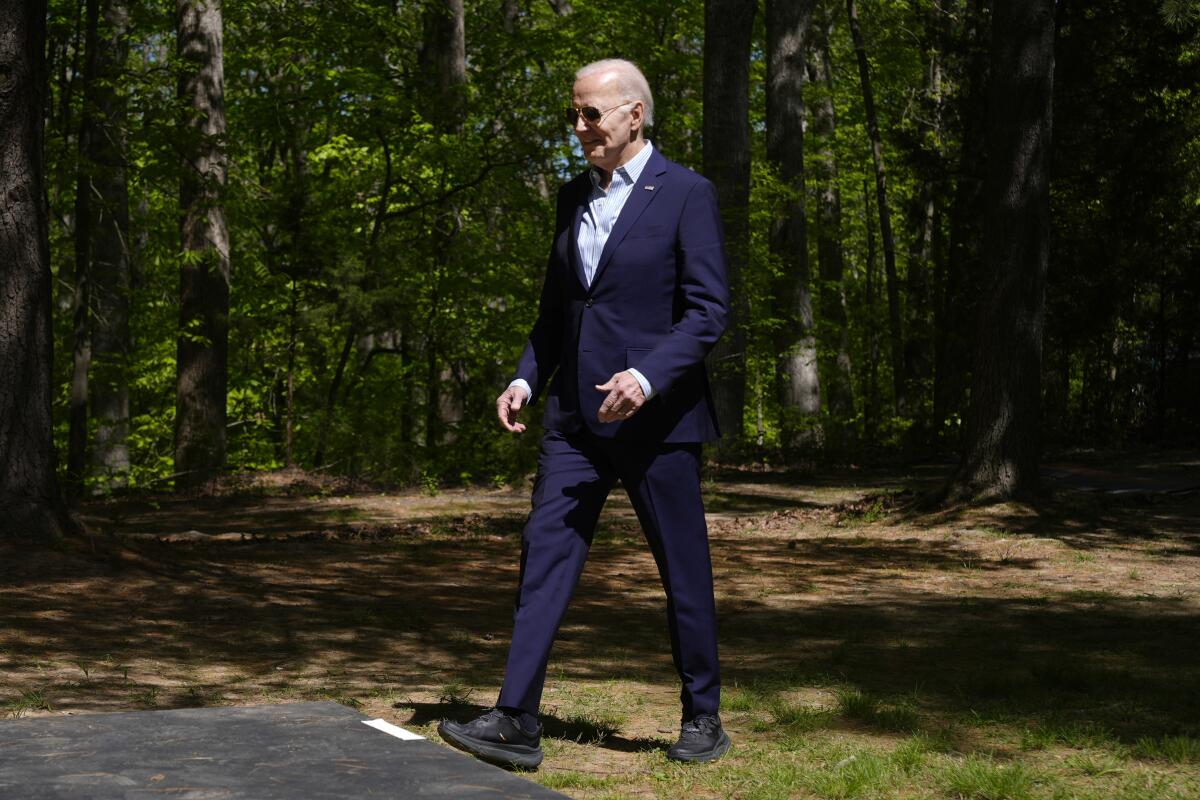 President Biden walks in a forested area. 