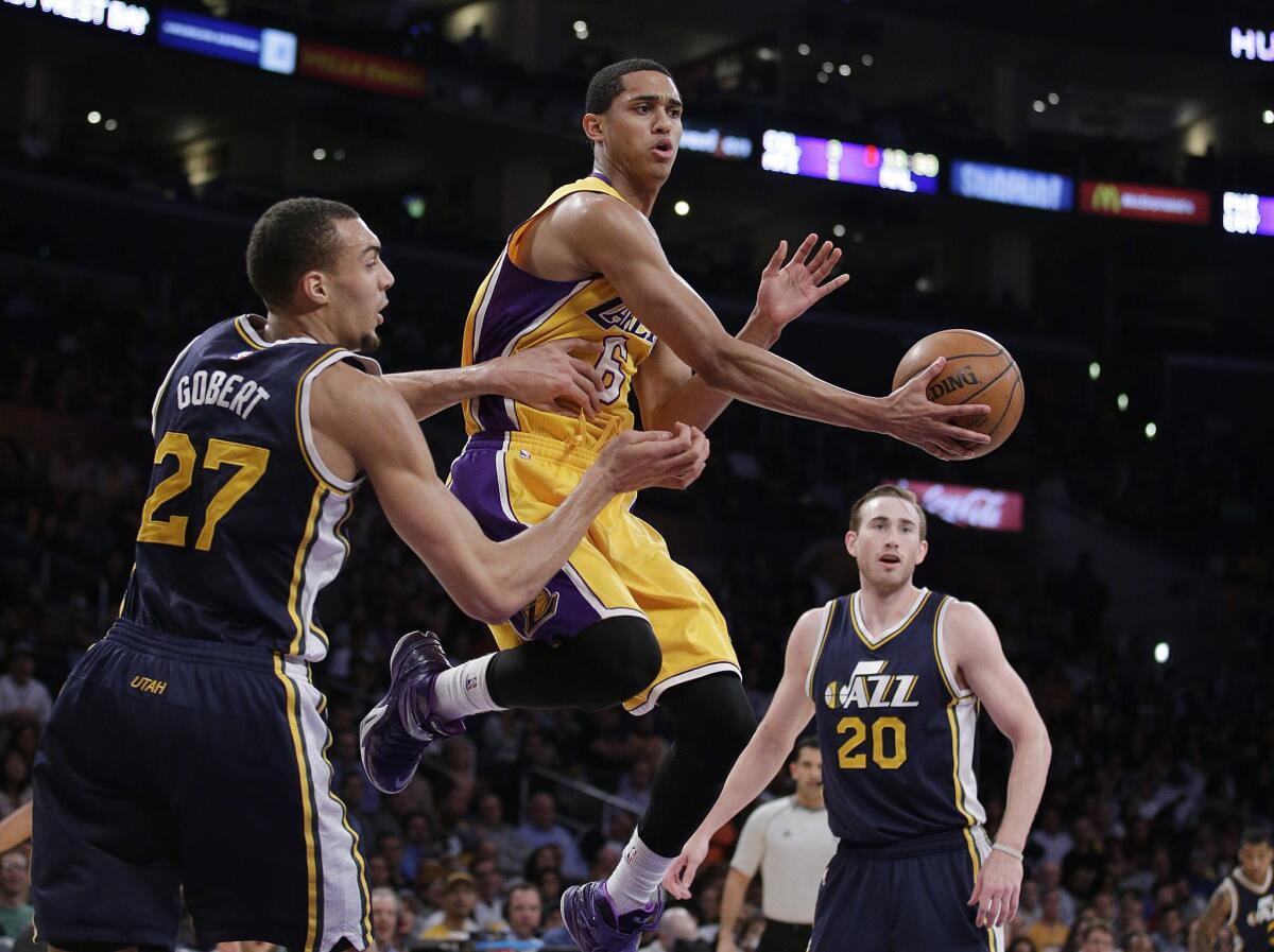 Lakers point guard Jordan Clarkson drops off a pass to a teammate after driving down the lane between Jazz center Rudy Gobert (27) and forward Gordon Hayward (20) in the second half.