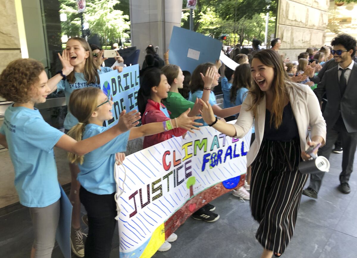 FILE - Kelsey Juliana, of Eugene, Ore., a lead plaintiff who is part of a lawsuit by a group of young people who say U.S. energy policies are causing climate change and hurting their future, greets supporters outside a federal courthouse, June 4, 2019, in Portland, Ore. Oregon-based youth climate activists say settlement talks with the U.S. Department of Justice have failed six years after they first filed a federal lawsuit in Eugene. The 21 plaintiffs alleged in the original lawsuit against the U.S. that they have a constitutional right to a climate that sustains life and that the government's actions have encouraged a fossil fuel economy despite scientific warnings about global warming. (AP Photo/Andrew Selsky, File)