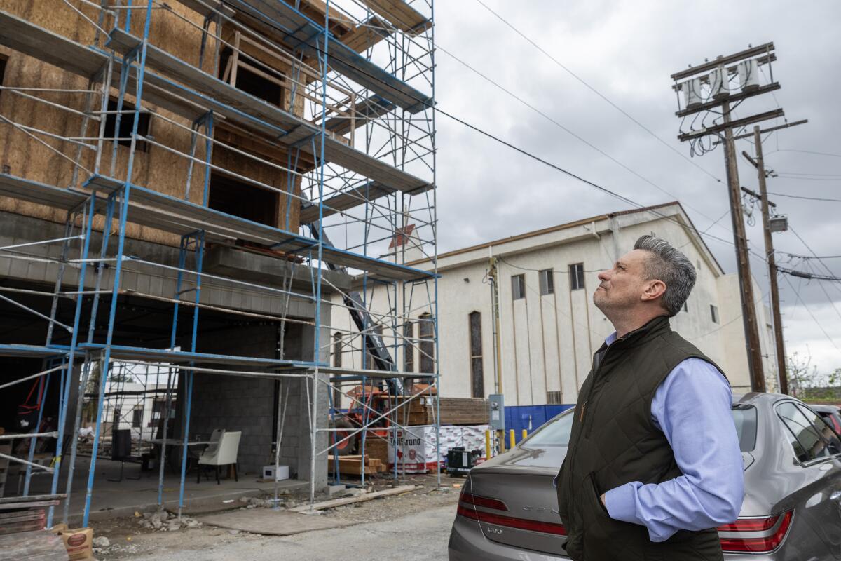 A man looks up a a building under construction.