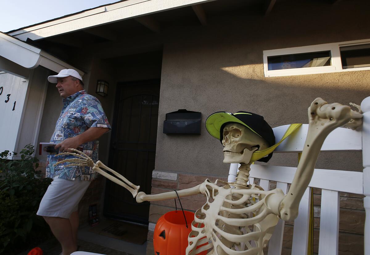 A congressional candidate going door to door passes a Halloween skeleton in a front yard.