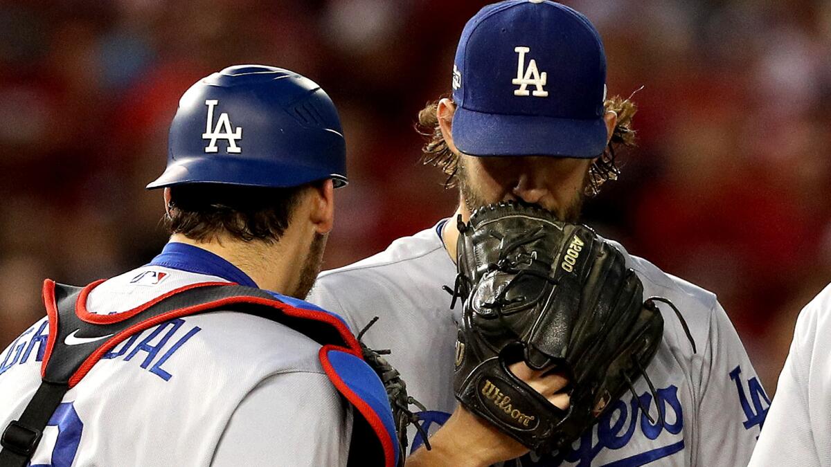 Dodgers ace Clayton Kershaw confers with catcher Yasmani Grandal during Game 1 of a National League division series Friday.