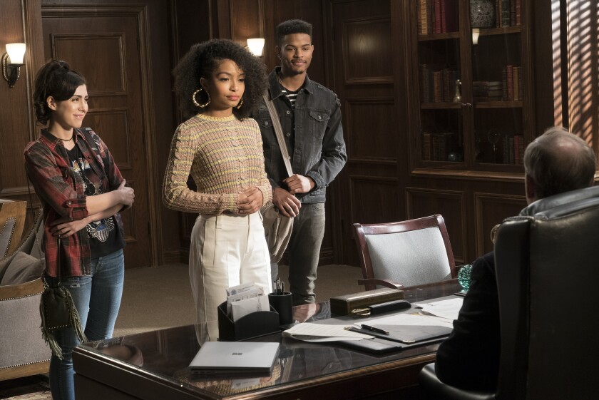 Three college students in an administrator's office.