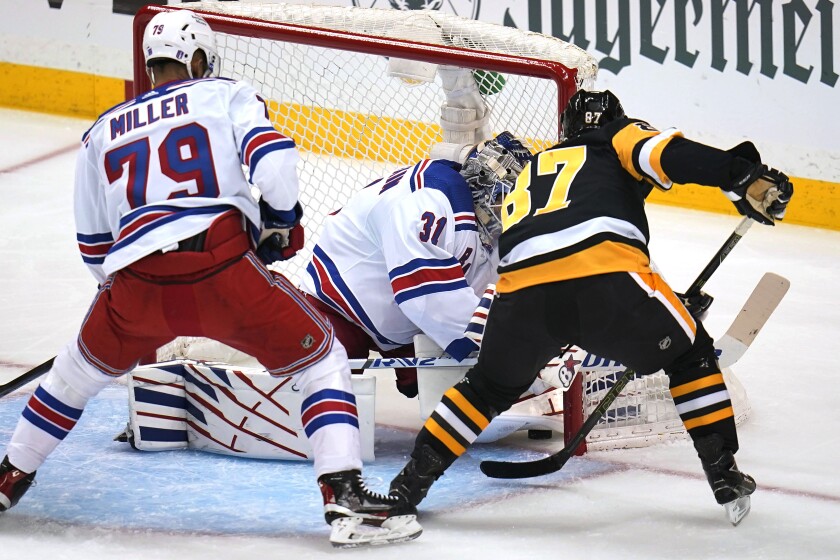 Pittsburgh Penguins' Sidney Crosby (87) pokes the puck under the pad of New York Rangers goaltender Igor Shesterkin (31) for a goal with K'Andre Miller (79) defending during the first period in Game 4 of an NHL hockey Stanley Cup first-round playoff series in Pittsburgh, Monday, May 9, 2022. (AP Photo/Gene J. Puskar)
