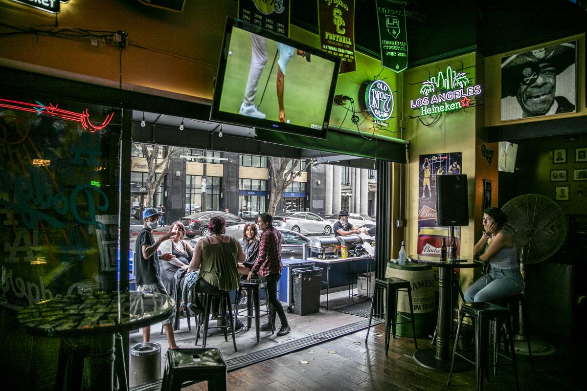 People sit outside on the patio of the Down & Out sports bar in downtown Los Angeles