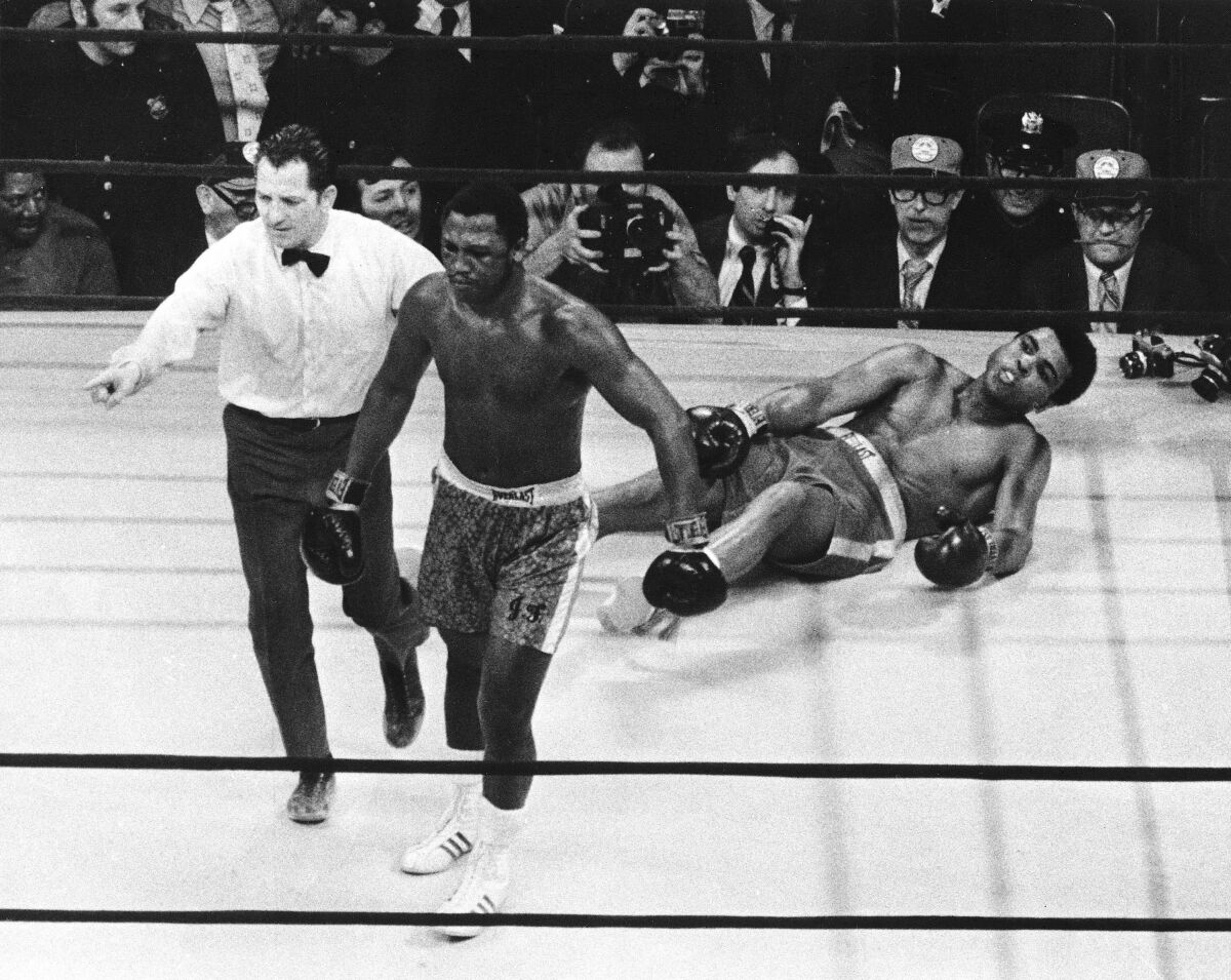 Dans cette photo d'archive du 8 mars 1971, le boxeur Joe Frazier est dirigé vers son coin par l'arbitre Arthur Marcante.