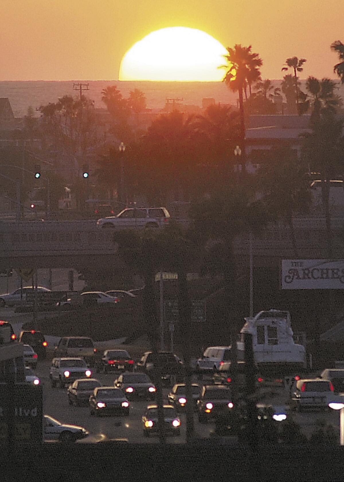 The setting sun is pictured from Cliff Drive above the Mariner's Mile stretch of West Coast Highway in Newport Beach.