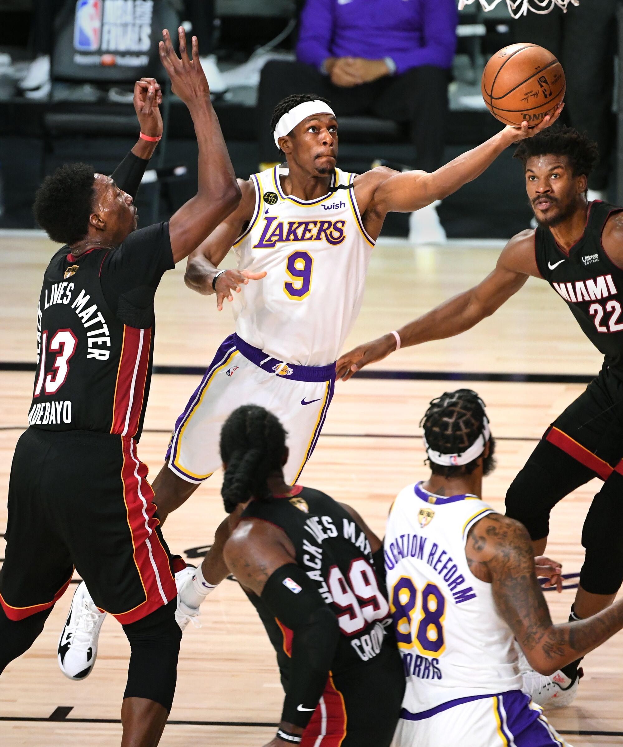 Lakers guard Rajon Rondo scores in front of Miami Heat forwards Bam Adebayo and Jimmy Butler.