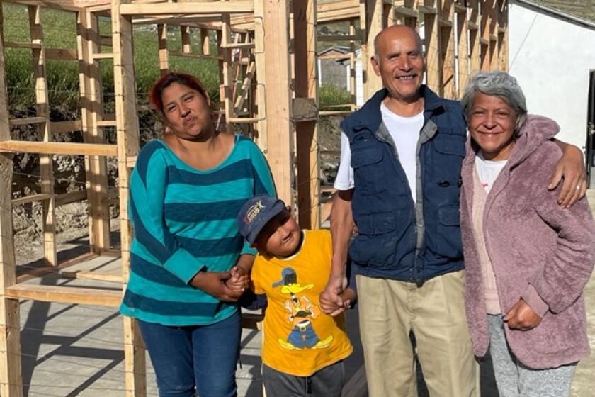 Pastor Octavio and his family in front of their new framed house.