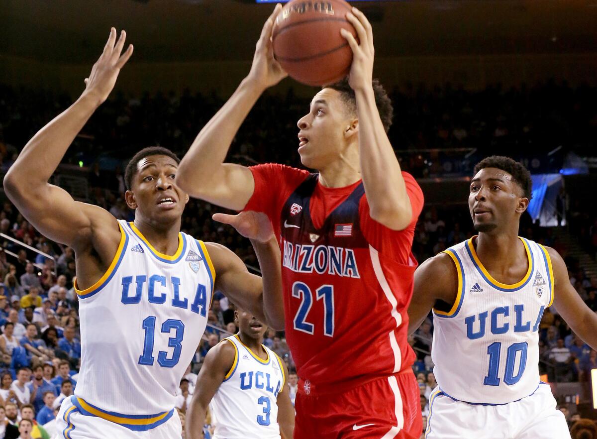 Arizona forward Chance Comanche looks to score inside against the defense of UCLA's Ike Anigbogu, left, and Isaac Hamilton during a Pac-12 game last season.