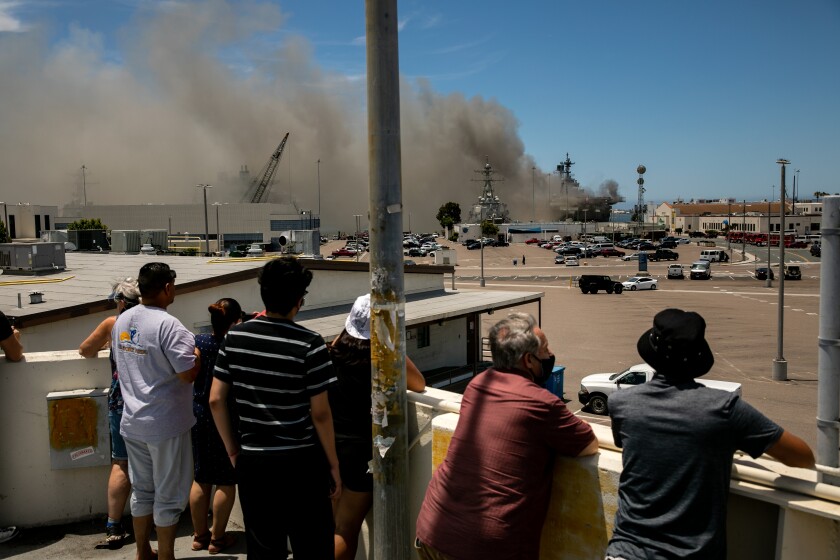 Passerby watch the fire aboard the USS Bonhomme Richard on Sunday, July 12, 2020 in San Diego, CA.