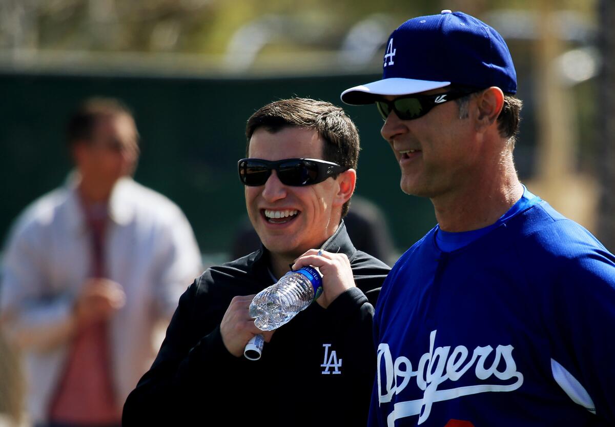 Andrew Friedman, Dodgers' president of baseball operations, shares a light moment with Manager Don Mattingly during a workout Friday. Now they have to set their roster for opening day.