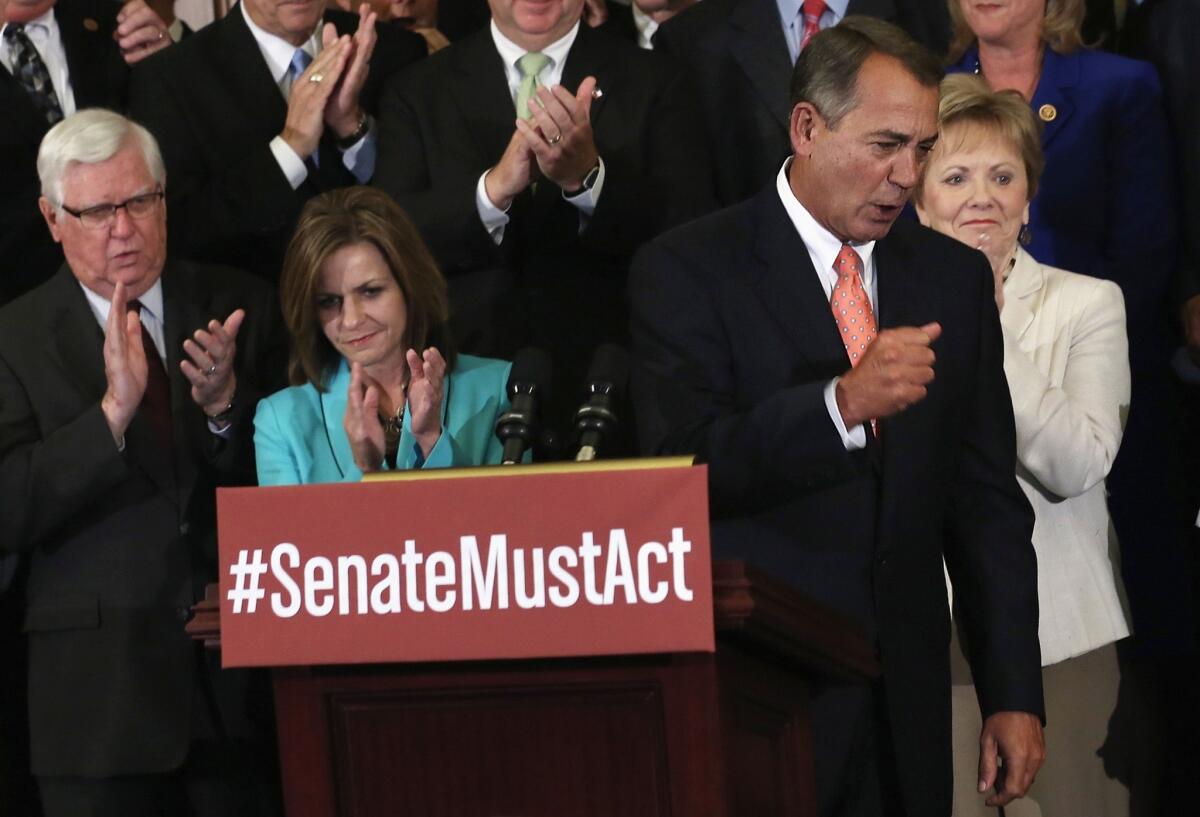 House Speaker John A. Boehner (R-Ohio), at the podium, leads a rally of House Republicans after a vote Friday to pass a spending bill that bars funding for the 2010 healthcare law but keeps the government running until Dec. 15.