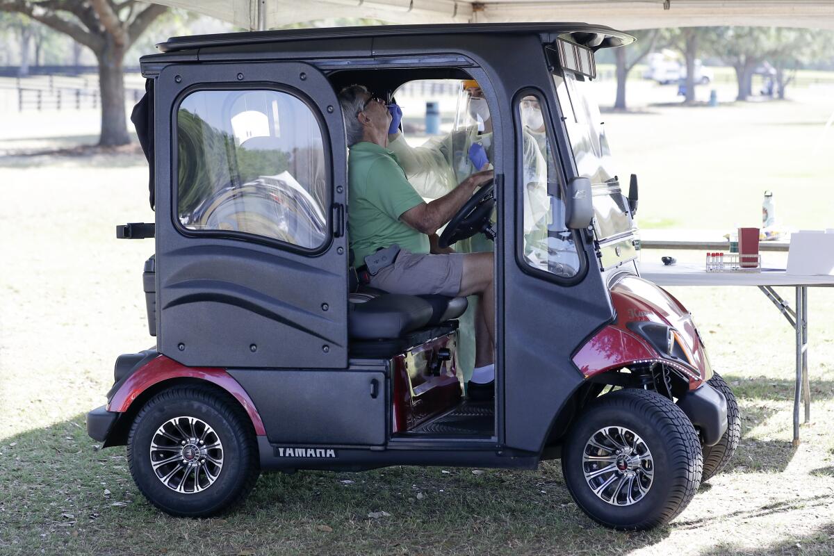 A resident in a golf cart is tested for COVID in the Villages, Fla. 