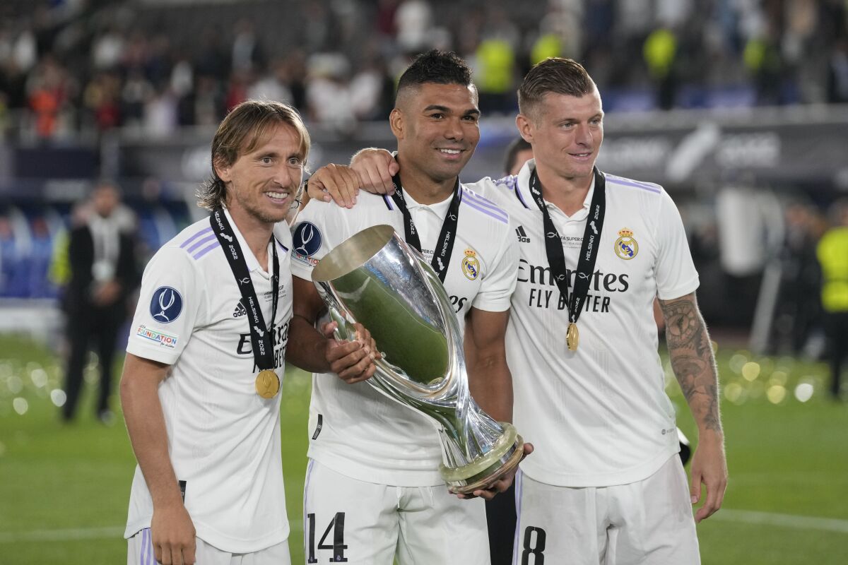 Real Madrid's Luka Modric, left, Real Madrid's Toni Kroos, right, and Real Madrid's Casemiro pose for a photograph as celebrate with the trophy after winning the UEFA Super Cup final soccer match between Real Madrid and Eintracht Frankfurt at Helsinki's Olympic Stadium, Finland, Wednesday, Aug. 10, 2022. Real Madrid won 2-0. (AP Photo/Antonio Calanni)