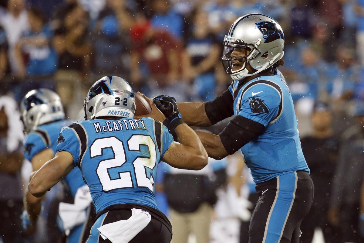 Panthers quarterback Cam Newton prepares to hand off to running back Christian McCaffrey during the first half Thursday night.