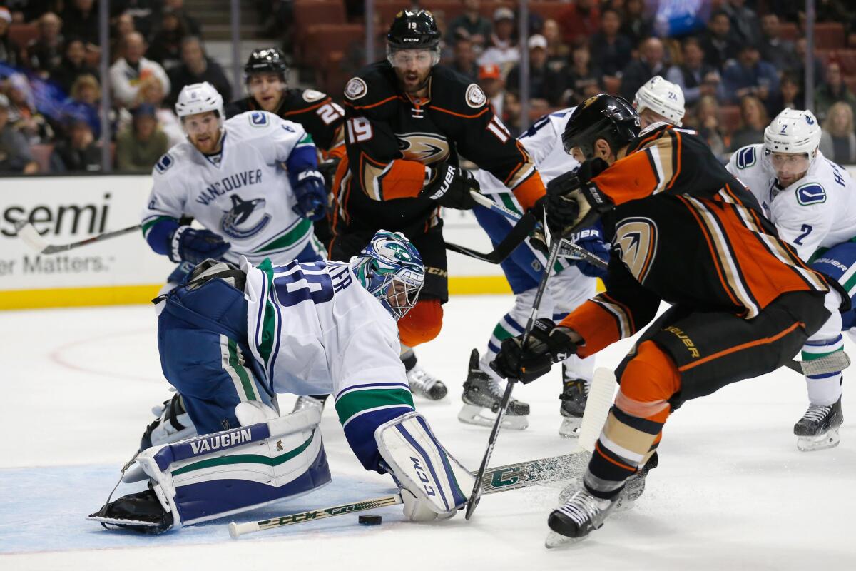 Vancouver goalie Ryan Miller tries to knock the puck away from from Ducks forwards Chris Stewart and Patrick Maroon during the first period of a game Nov. 30.