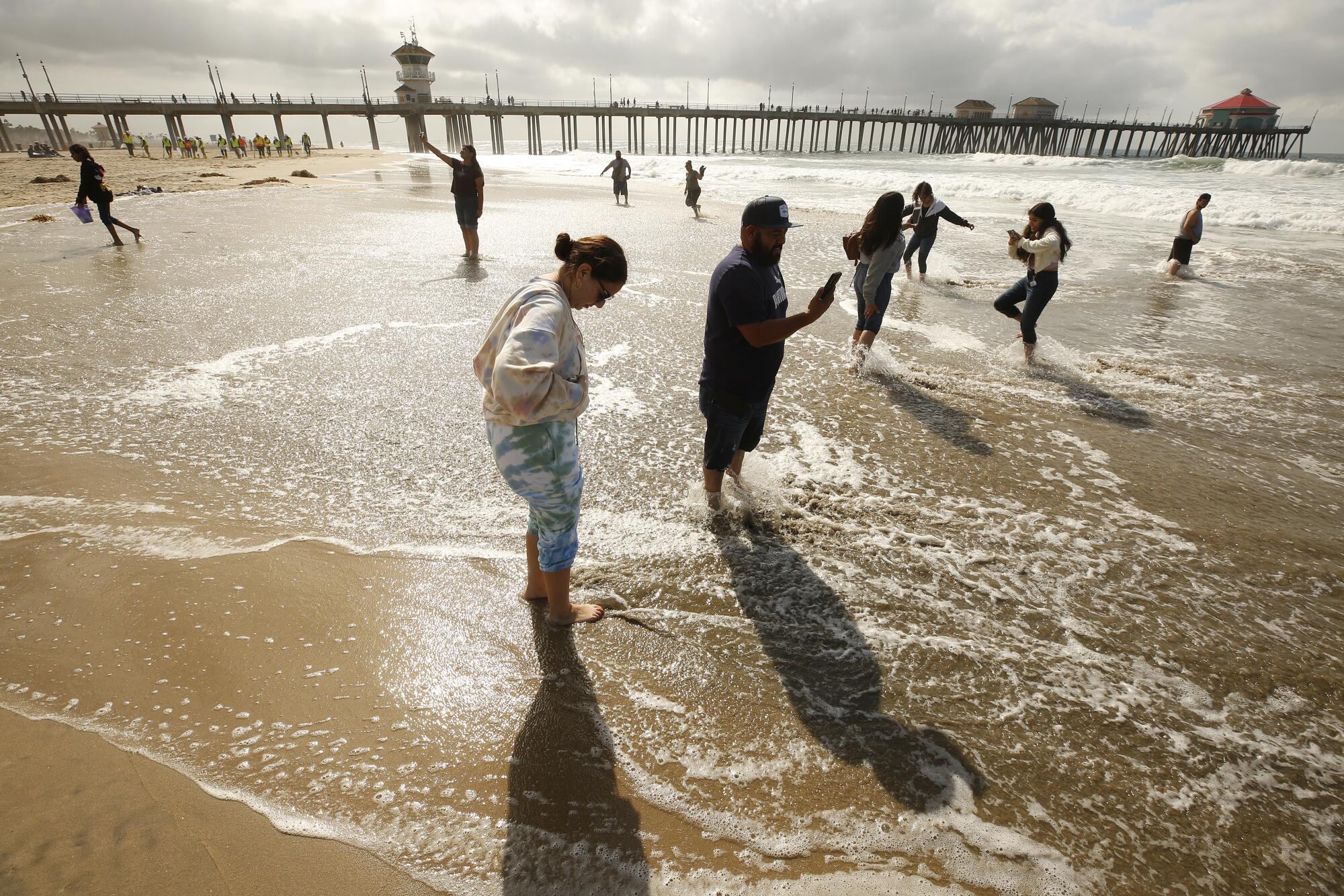 A family wade into shallow water at the beach