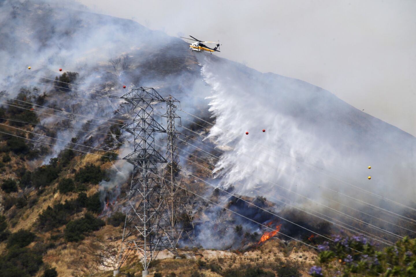 A fire-fighting helicopter drops water on the Duarte fire at 500 acres with 0% containment.