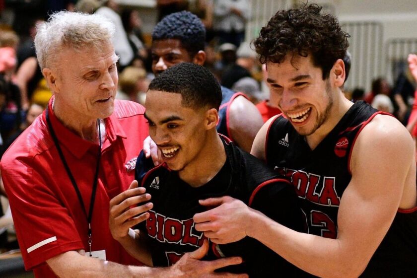 Biola University coach Dave Holmquist celebrates with players during a game.