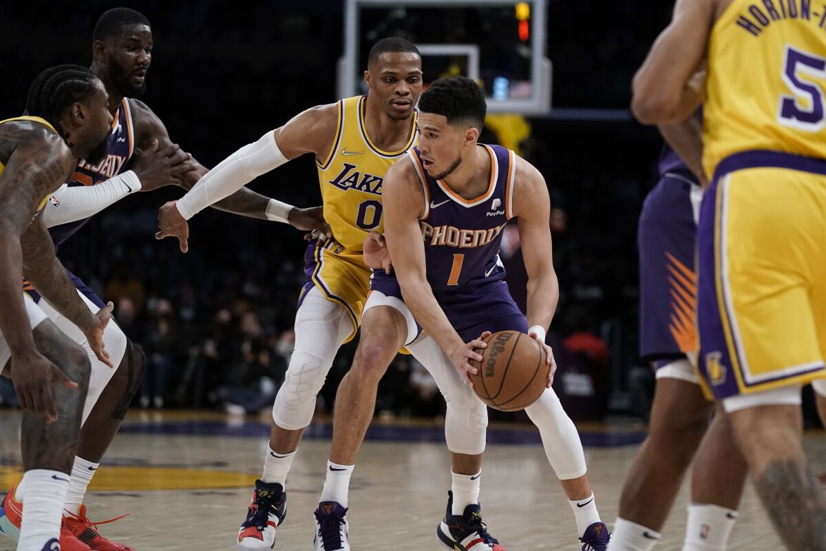 Phoenix Suns guard Devin Booker, center right, is pressured by Lakers guard Russell Westbrook during the first half.