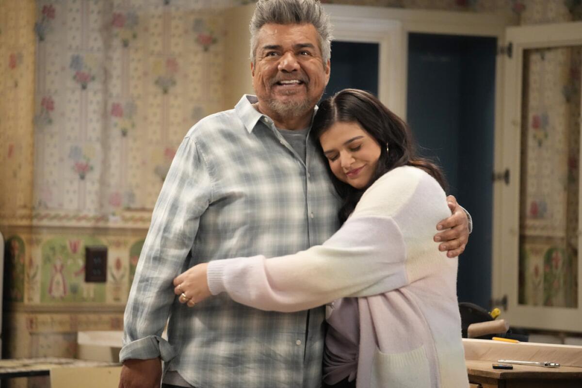 An adult daughter hugs her father in the kitchen