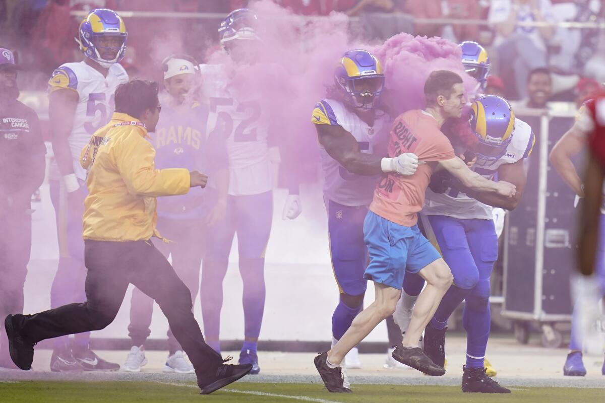 As security pursues, a man at the 49ers home game Monday is hit by Rams Takkarist McKinley and Bobby Wagner, right.