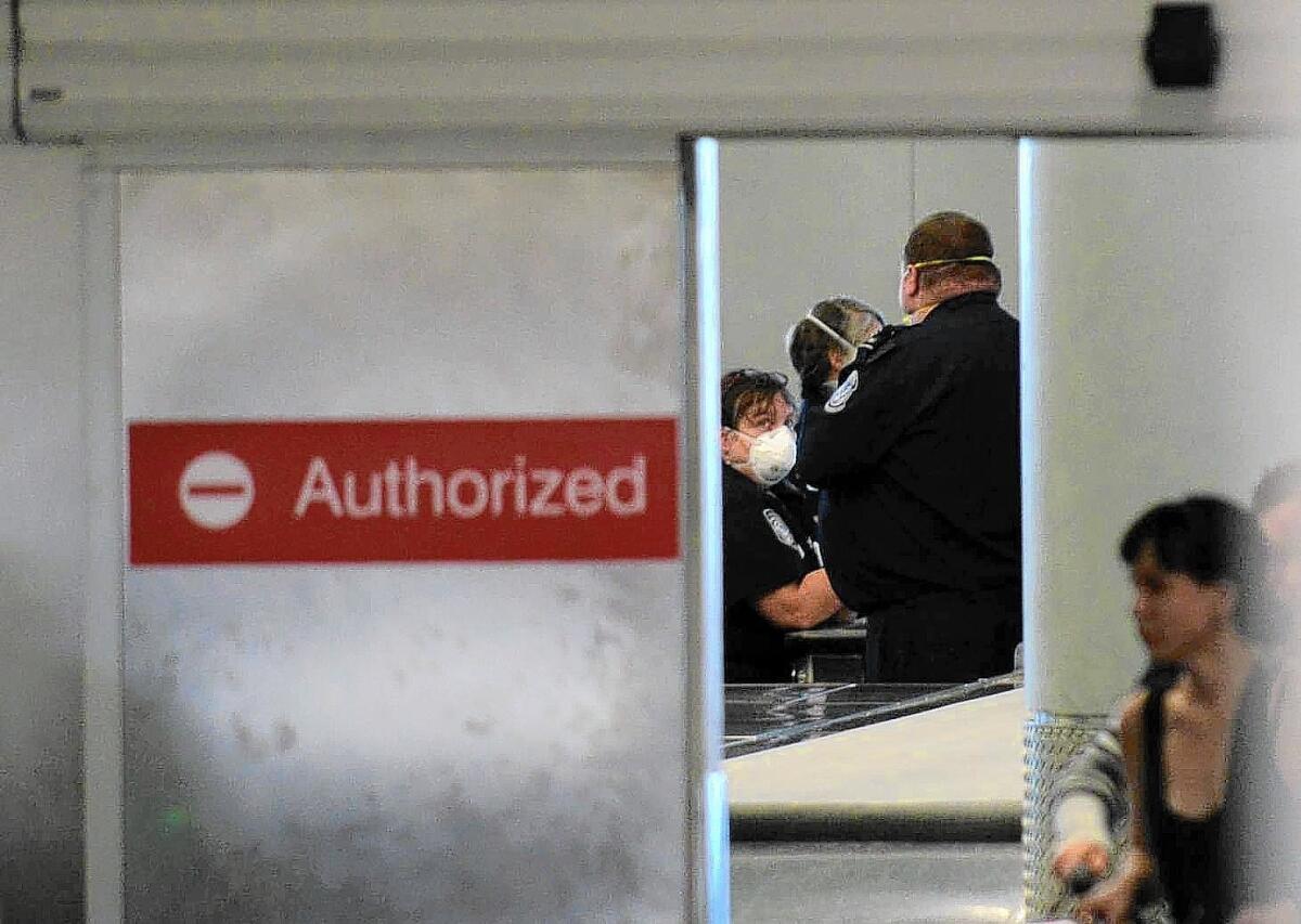 To keep Ebola from spreading, federal officials have announced new screening procedures for international travelers arriving at five U.S. airports. Above, customs officers at the Newark, N.J., airport.