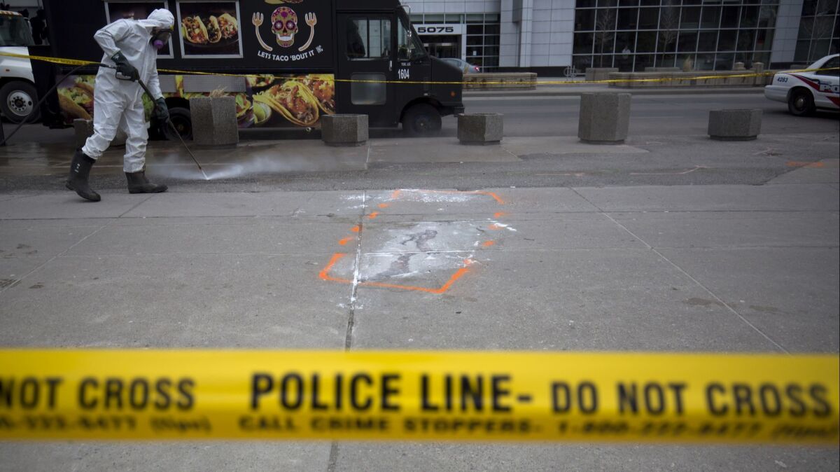A hazmat worker scrubs a Toronto sidewalk near an outline of a body after a driver swerved onto the sidewalk in a rental van. Ten people were killed. The driver, who has been charged with murder, is associated with the "incel" community, men who are involuntarily celibate.