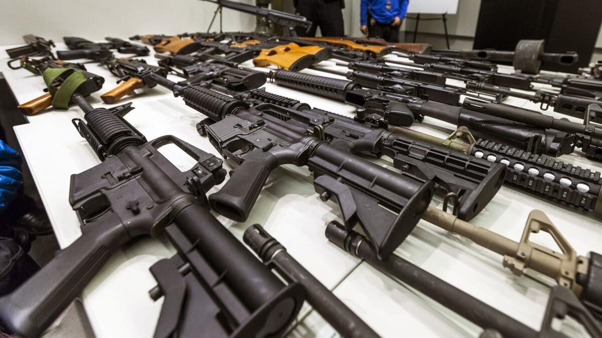 A variety of military-style semi-automatic rifles obtained during a buyback program are displayed at Los Angeles police headquarters. Owners of semi-automatic guns with "bullet buttons" were required to register them with the state by the end of June.