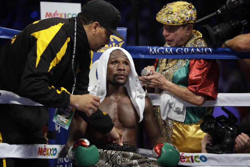 Floyd Mayweather is tended to by his corner, including cut man Rafael Garcia, right, during his 2014 match with Marcos Maidana.