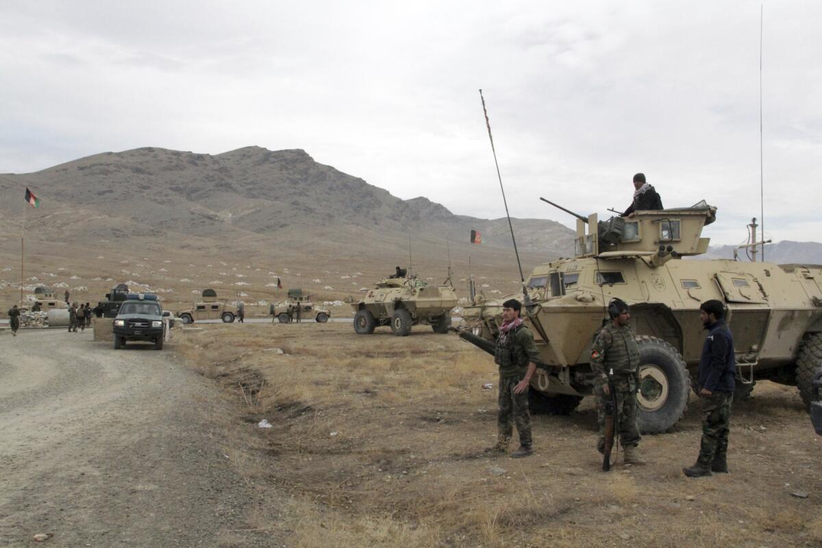 Troops and armored military vehicles next to a dirt road