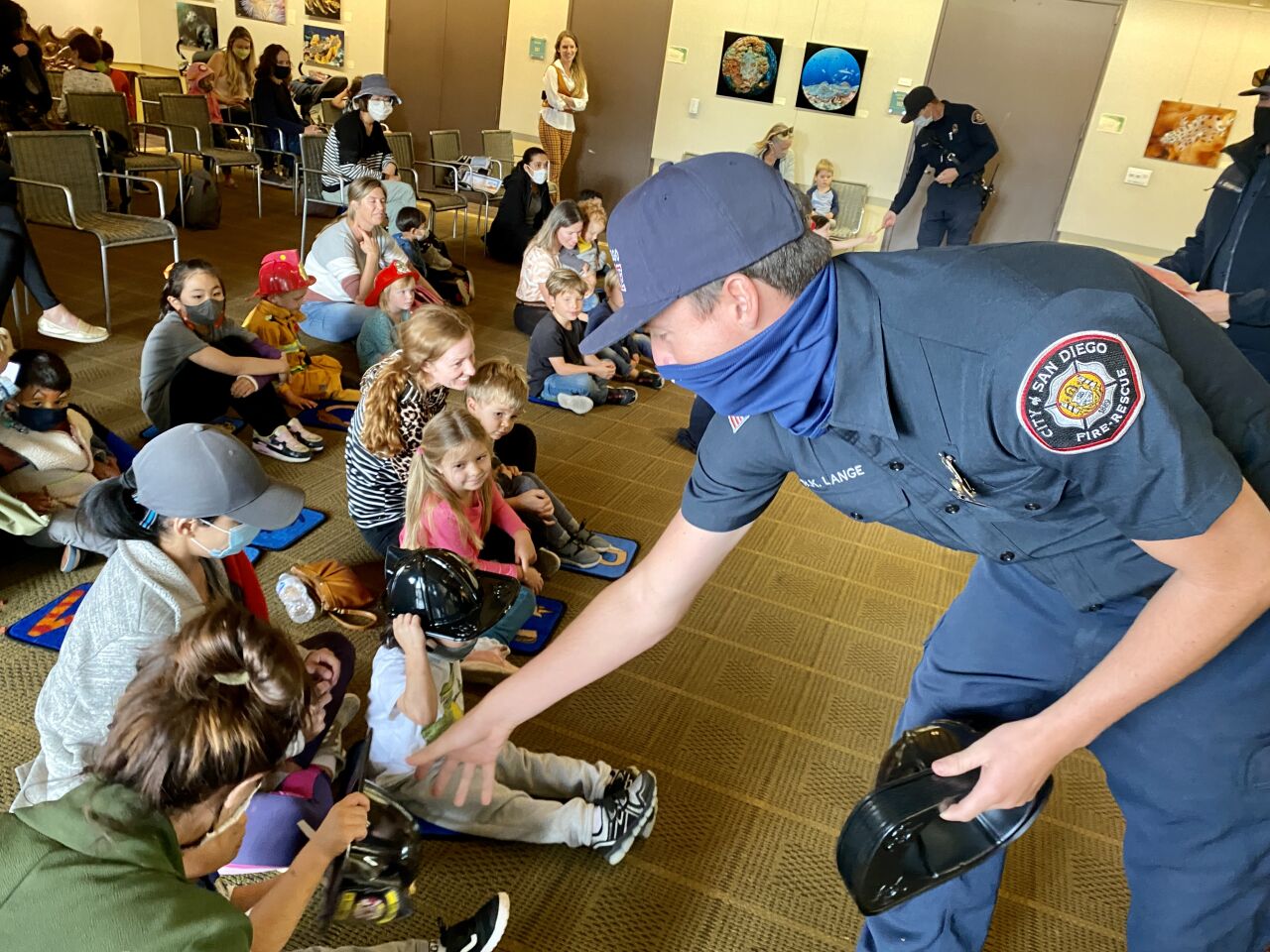 A La Jolla firefighter distributes hats and stickers to visitors at the La Jolla/Riford Library on Nov. 4.