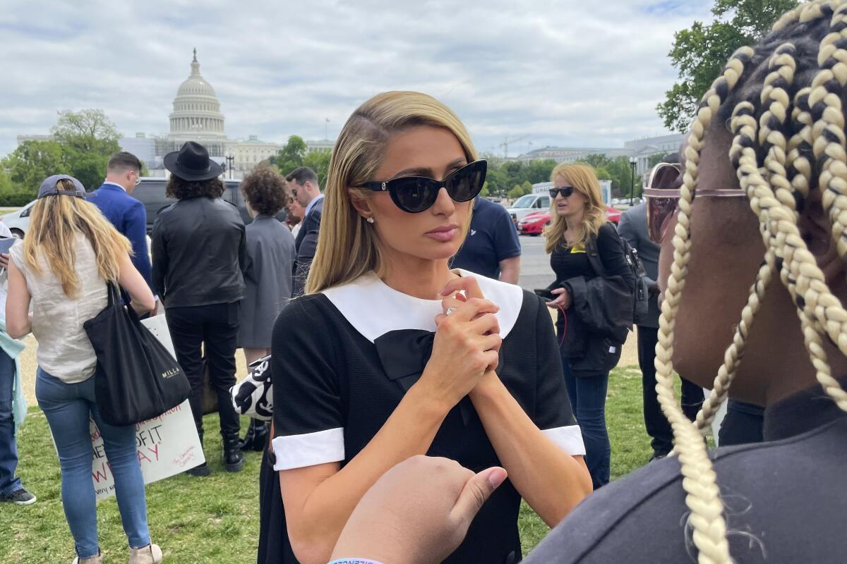 Paris Hilton talks outside, with the U.S. Capitol building in the background