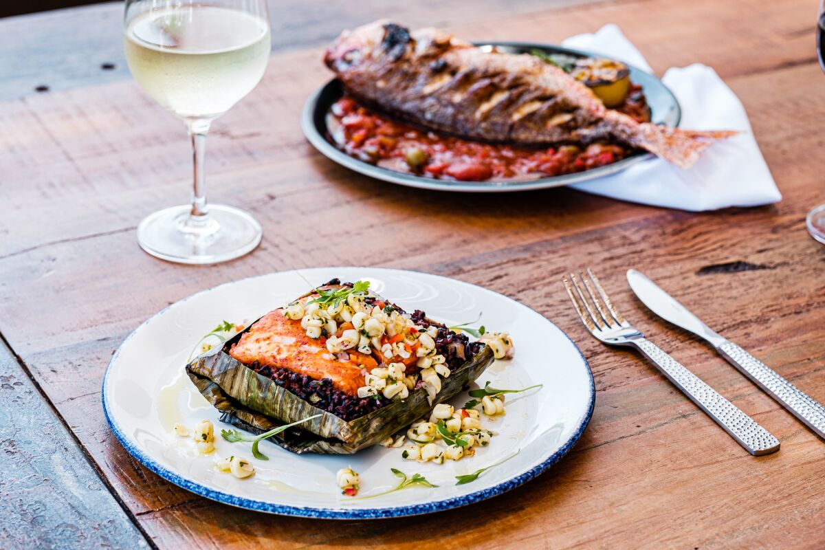 The roasted Chilean seabass pibil, foreground, and whole roasted huachinango Veracruz at Fresco Cocina.