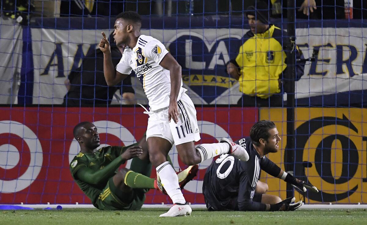 Los Angeles Galaxy forward Ola Kamara, center, celebrates his goal as Portland Timbers defender Larrys Mabiala, left, and goalkeeper Jake Gleeson lie on the ground during the first half of a Major League Soccer game, Sunday, March 4, 2018, in Carson, Calif.