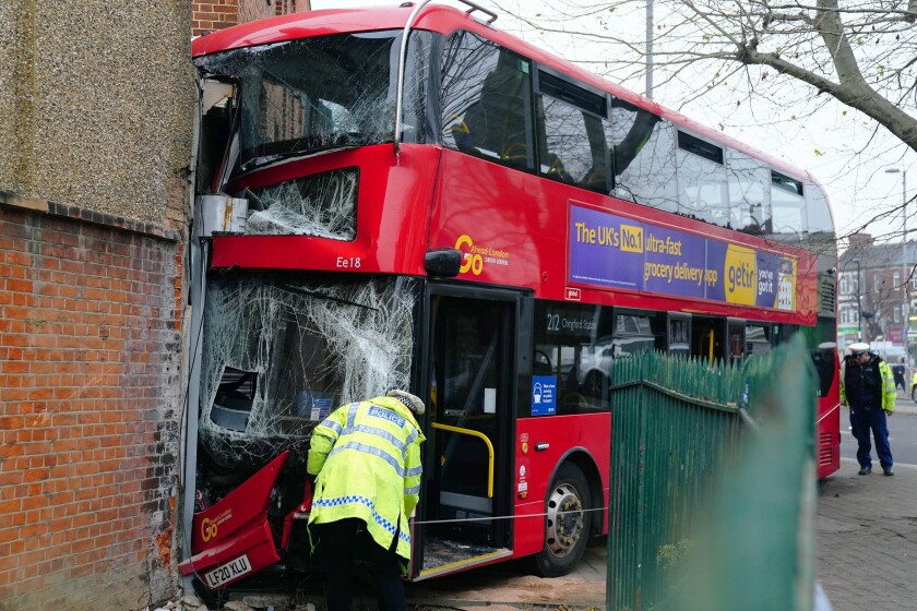 Emergency services at the scene on the Broadway after a bus crashed into a building, in Highams Park, east London, Tuesday, Jan. 25, 2022. (Victoria Jones/PA via AP)