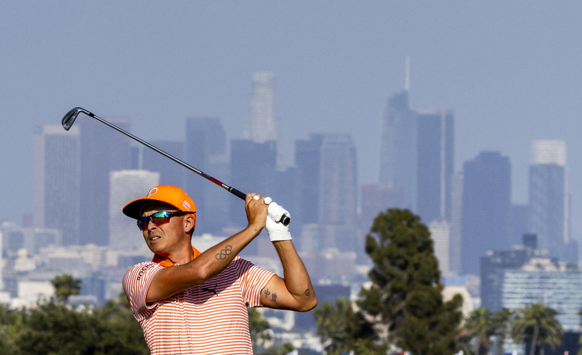 Rickie Fowler hits a fairway shot during the final round of the U.S. Open with the downtown L.A. skyline in the background.