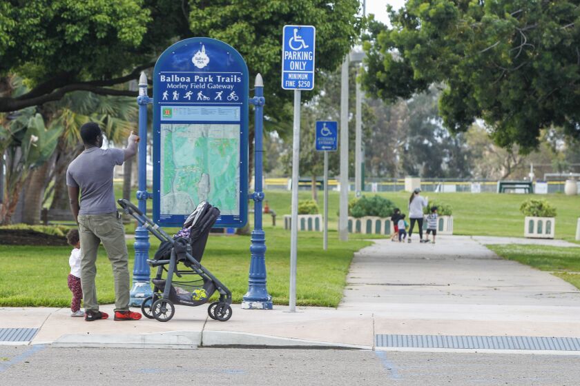 Yaw Anokwa (left) and his daughter Lexi Anokwa, 1, take a walk at Morley Field in Balboa park on April 21, 2020 in San Diego, California. The city of San Diego has opened certain parks to the general public as an easing of restrictions from the COVID-19 pandemic.
