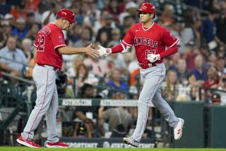 Los Angeles Angels designated hitter Shohei Ohtani, right, clasps hands with third base coach Bill Haselman.