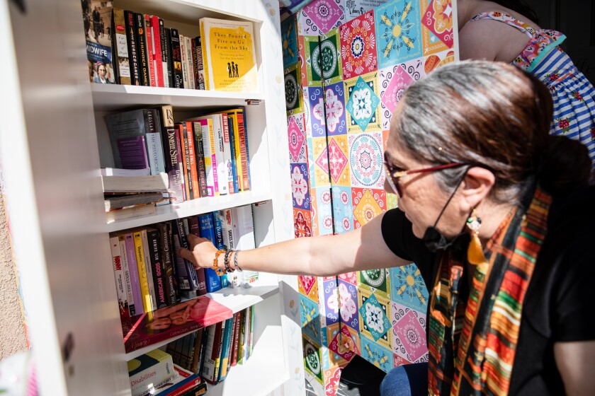 Katia Padilla pulls out a book from her Free Little Library at her Chula Vista home on Tuesday, March 30.